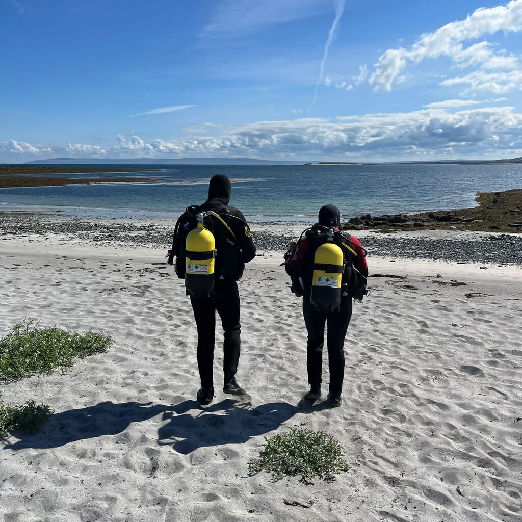 Two scuba divers walking on the beach ready for scuba